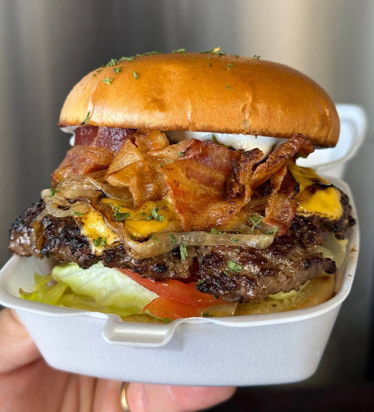 Boxer Bros burger stacked with beef, bacon, melted cheese, onions, lettuce and tomato